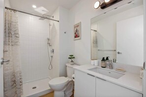 Ein modernes Badezimmer mit Dusche, Toilette, Waschbecken und einem großen Spiegel.