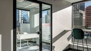 A modern office space with a glass door, a white desk, and a green chair. - Steps to Nightlife & Dining, Gym, Sauna, Stampede (Calgary)