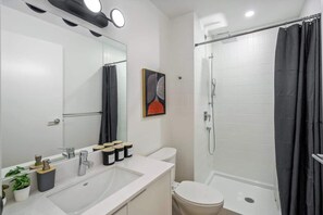 A modern bathroom with a large mirror, white sink, and a shower area with a black curtain. - Gym, Pool Table, Downtown, Cultural Hot Spot (Calgary)