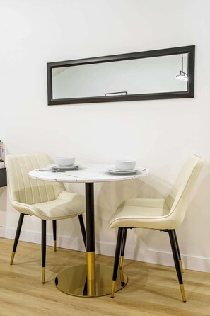 A dining area with a round table, two chairs, and a mirror on the wall. - Gym, Pool Table, Downtown, Cultural Hot Spot (Calgary)