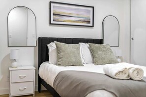 A neatly arranged bedroom with a bed, two bedside tables, a nightstand, and a framed artwork on the wall. - Gym, Pool Table, Downtown, Cultural Hot Spot (Calgary)