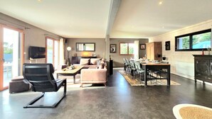A spacious living area with a sofa, a dining table with chairs, and a kitchen area with cabinets and a window. - Spacious family home near Vannes, Terémer (Saint-Nolff)