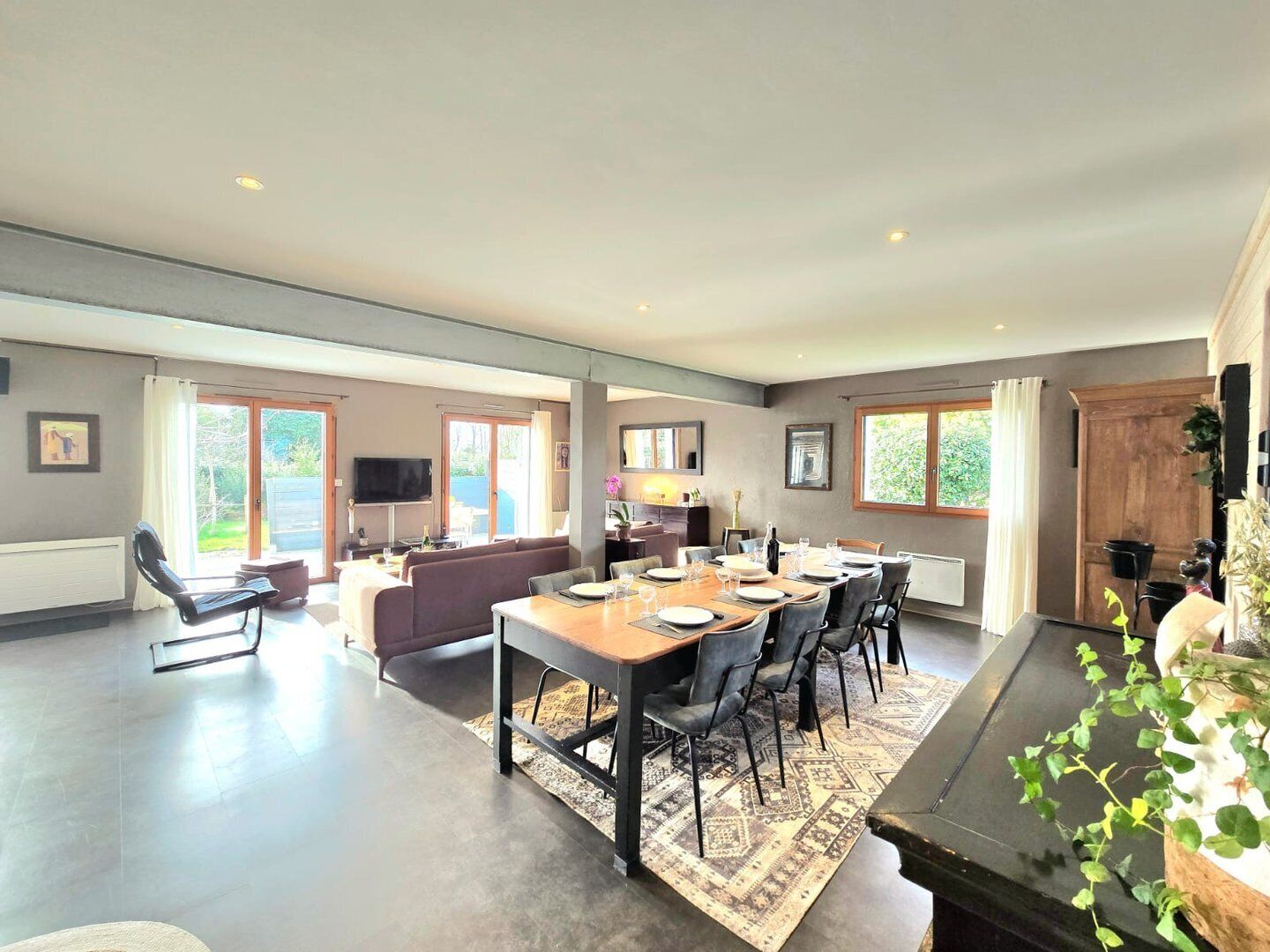 A spacious living area with a dining table set for six, a sofa, and a TV.