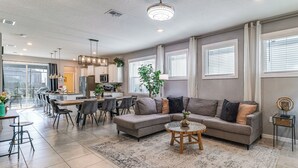 En moderne stue med en modulsofa, spiseplads og et køkken i baggrunden.