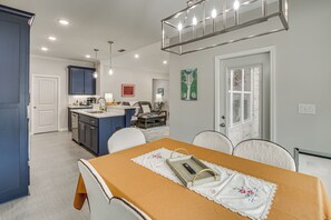 A modern kitchen with dark cabinets, a dining area with a table set for two, and a living space with a sofa and coffee table. - Steps to Fairway: Hot Springs Village Golf Retreat (Hot Springs Village)