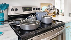 A kitchen with a stainless steel stove, pots, and pans on the burners.