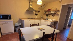 A compact kitchen with white cabinets, a dining table, and a microwave.