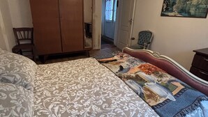 A bedroom with a bed, a wardrobe, a chair, and a painting on the wall.