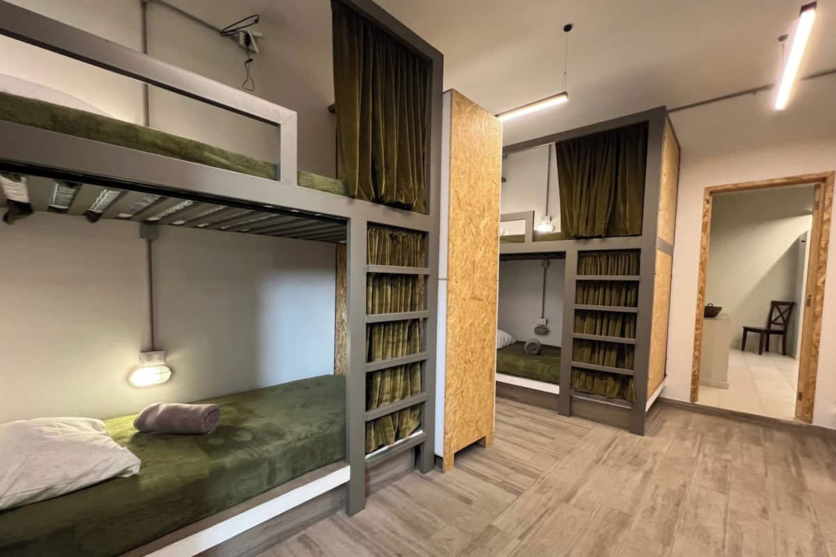 A modern, multi-level dormitory room with bunk beds, built-in shelves, and a wooden floor.
