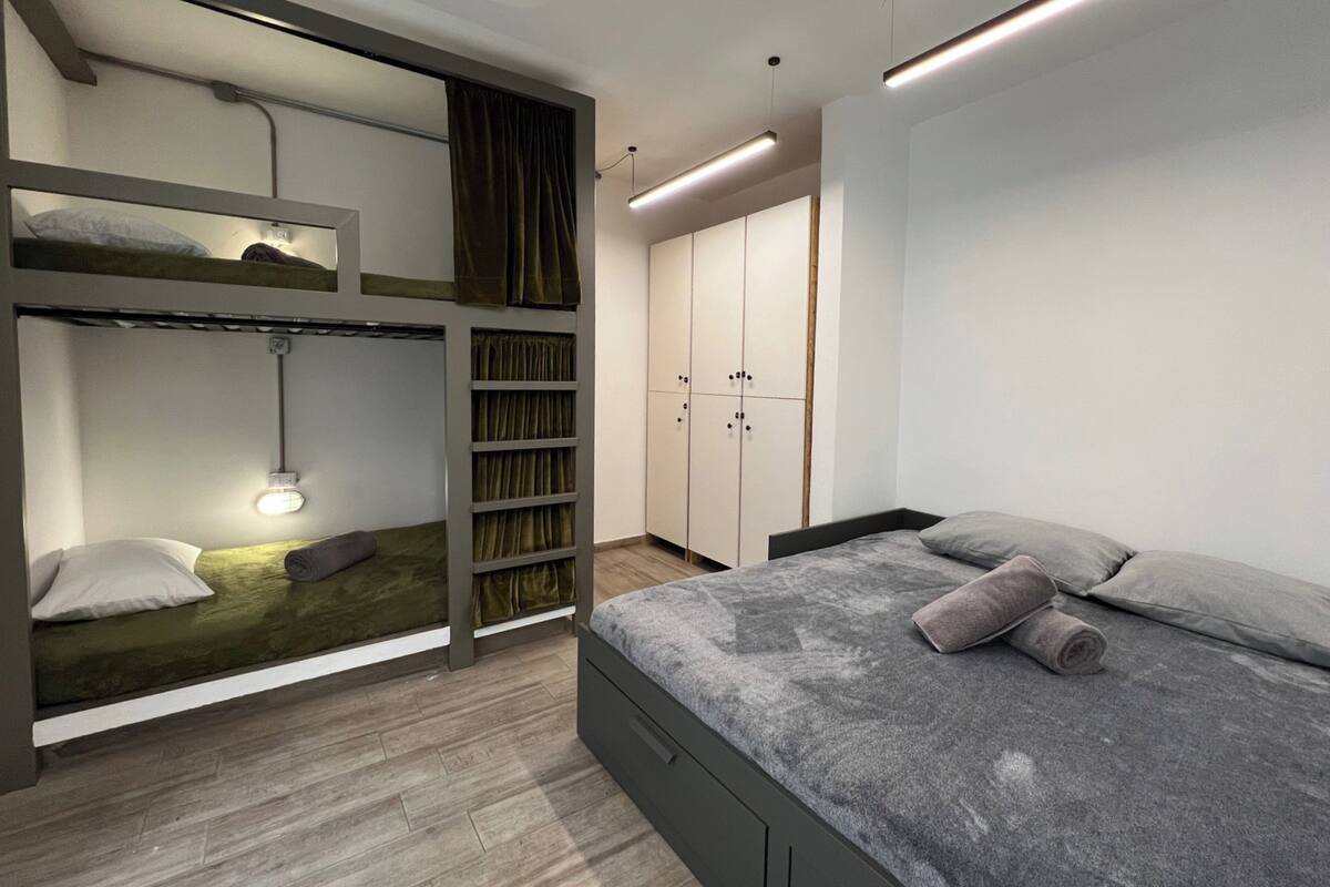 A modern bedroom with bunk beds, a wardrobe, and a bedside table.