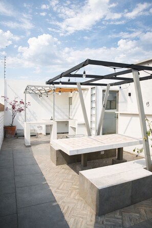 A modern outdoor patio with a pergola, seating area, and a small table. - NOMADIK HOSTEL (Puebla)