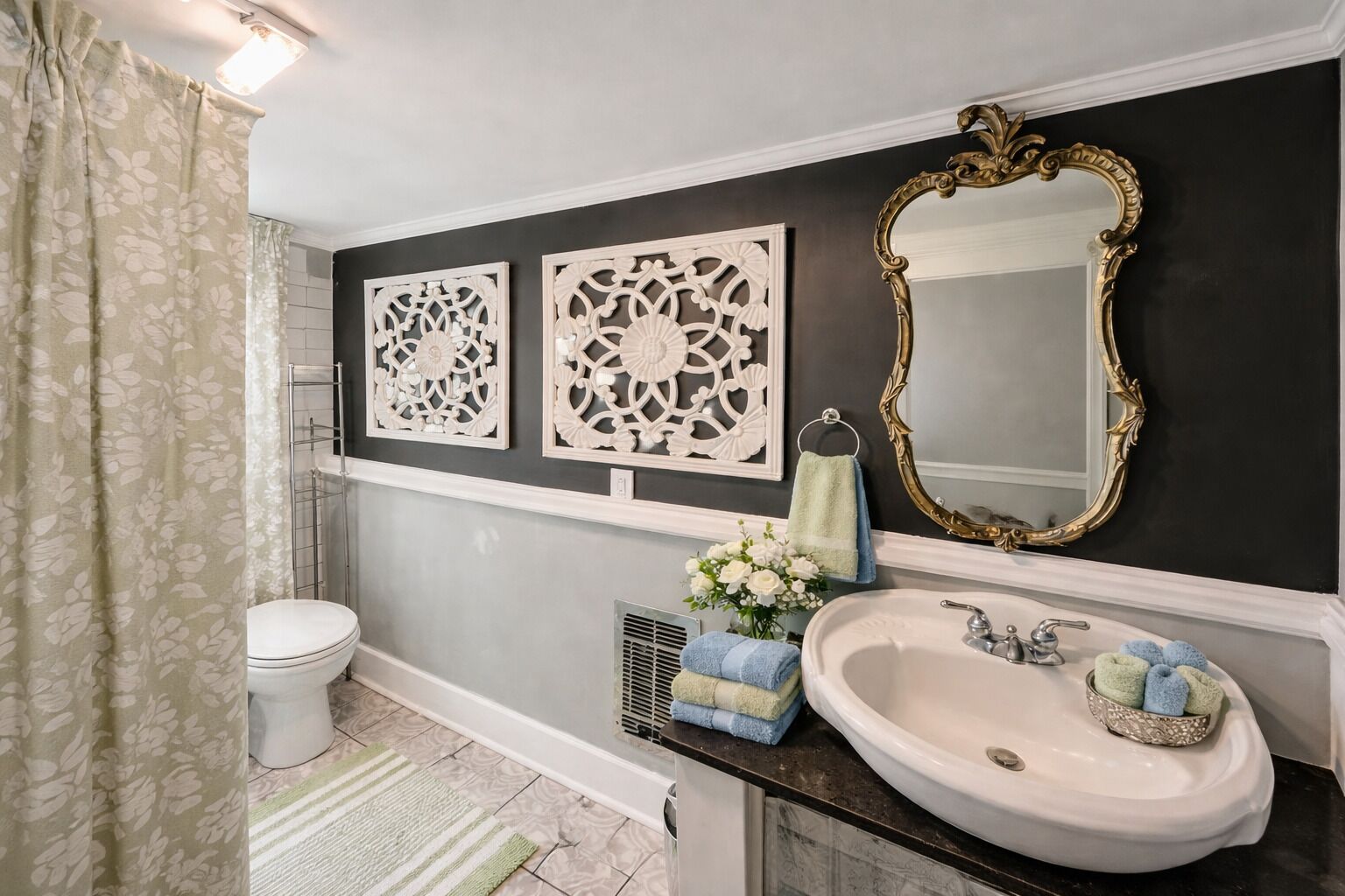 Un baño con inodoro, lavamanos y espejo. Cuenta con paneles decorativos en la pared y una cortina de ducha.