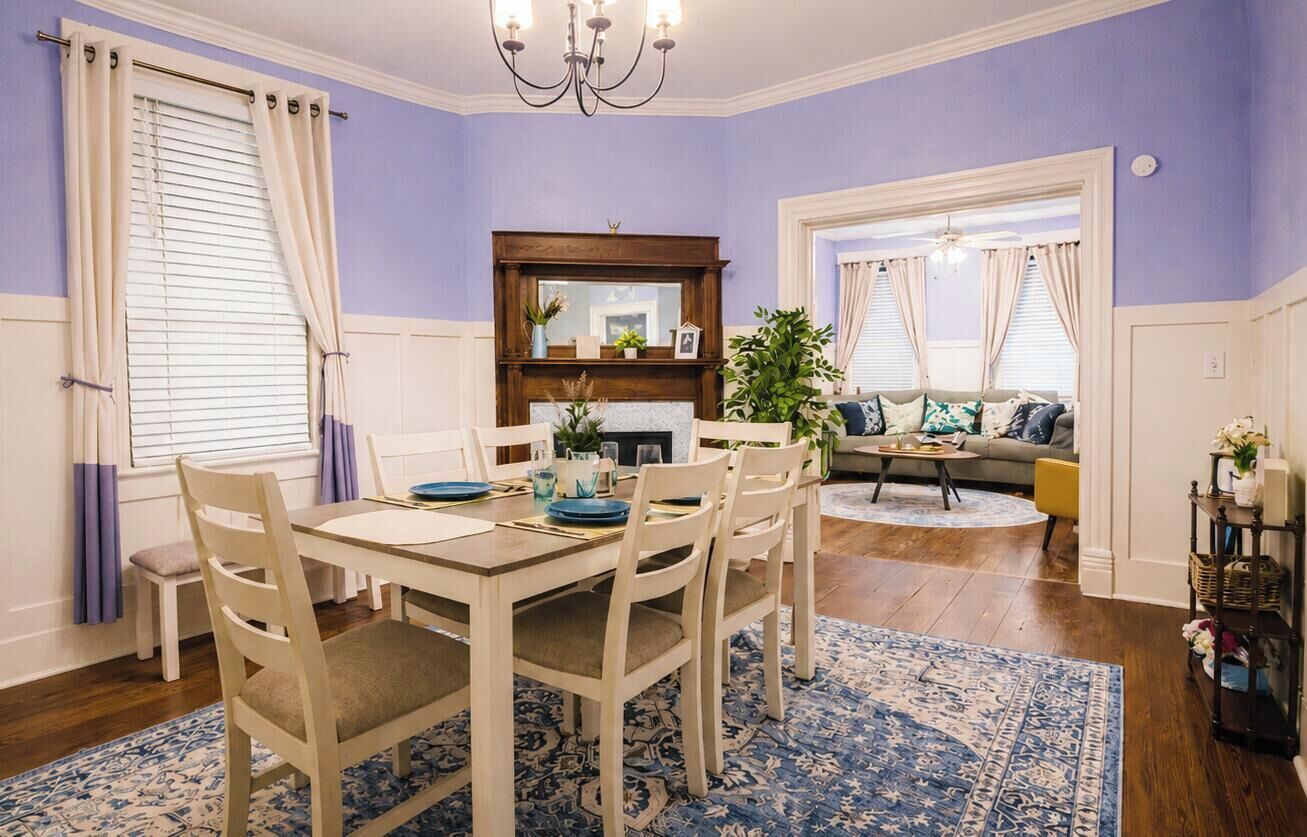 A dining area with a table and chairs, a fireplace, and a sofa in the background.