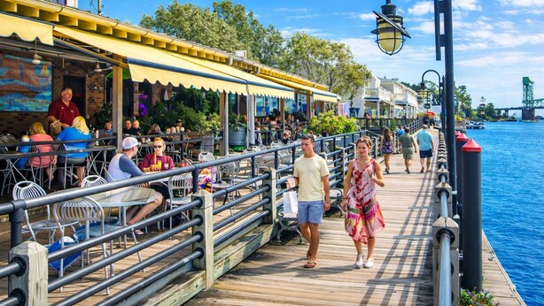 A wooden pier with outdoor seating, a view of the water, and a bridge in the background. - Historic Gem King Ste Walk to Downtown Riverwalk & Wedding Venues (Wilmington)