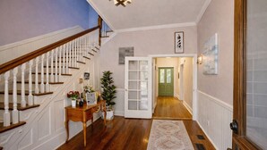 A hallway with a wooden staircase, a green door, and a white door leading to another room. - Historic Gem King Ste Walk to Downtown Riverwalk & Wedding Venues (Wilmington)