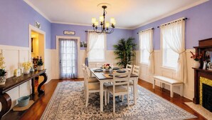 A dining room with a chandelier, a dining table set for four, and a fireplace. - Historic Gem King Ste Walk to Downtown Riverwalk & Wedding Venues (Wilmington)