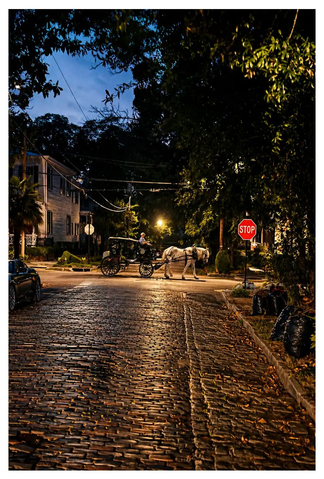 A cobblestone street with a horse-drawn carriage, a stop sign, and a building with a balcony.