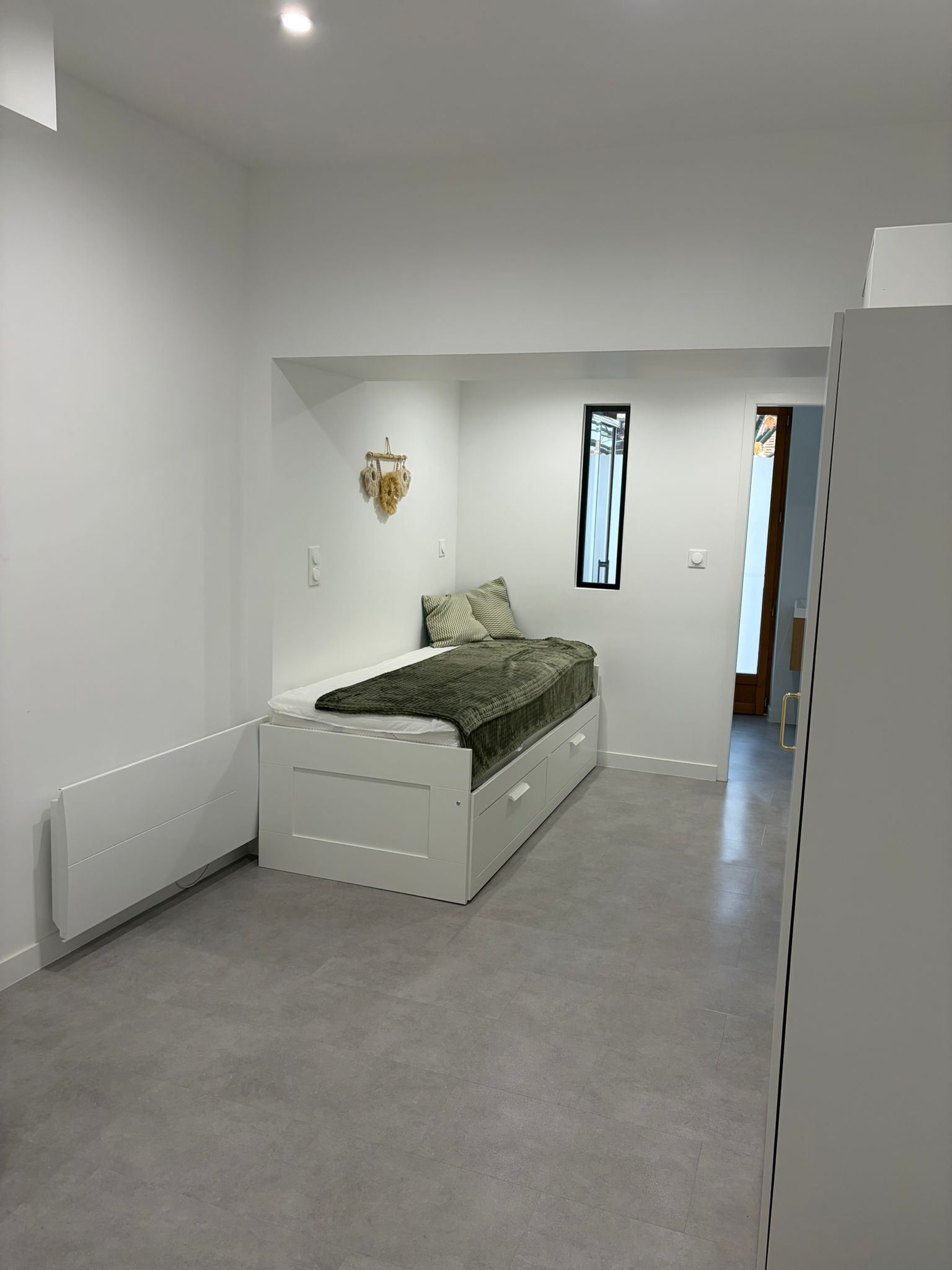 Een moderne slaapkamer met een enkel bed, een klein nachtkastje en een raam.