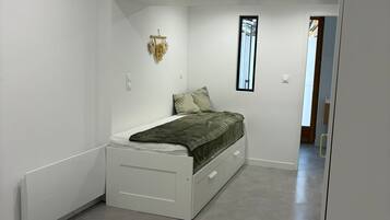 Een moderne slaapkamer met een enkel bed, een klein nachtkastje en een raam.