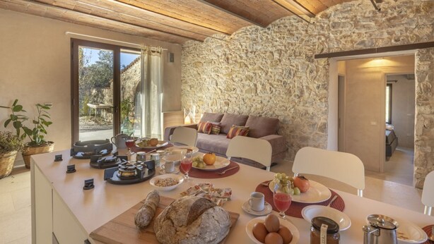 Un espace repas avec un mur en pierre, un plafond en bois et une table dressée avec de la nourriture et des boissons.