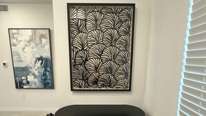 A room with a black cabinet, a large abstract painting, and another painting on the wall. - Brand-new construction furnished with new items of 2/2 condo  Lakewood Ranch, FL (Lakewood Ranch)