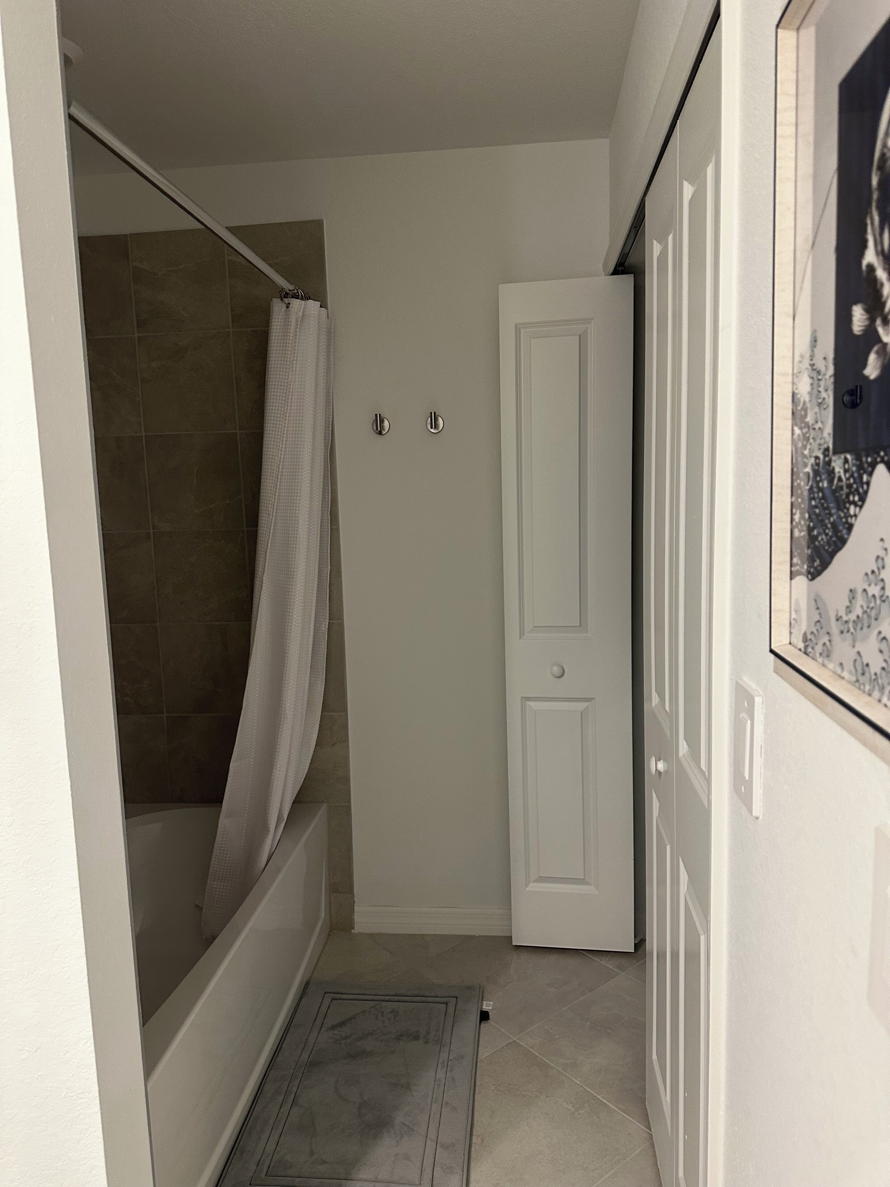 Een badkamer met een douche, een deur en een betegelde vloer.