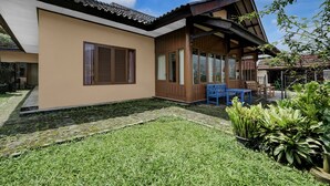 Una casa moderna con un patio grande, una terraza de madera y un pequeño jardín.
