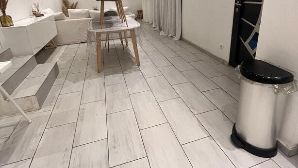 Ein modernes Wohnzimmer mit Flachbildfernseher, einer Couch, einem Sessel und einer Treppe.