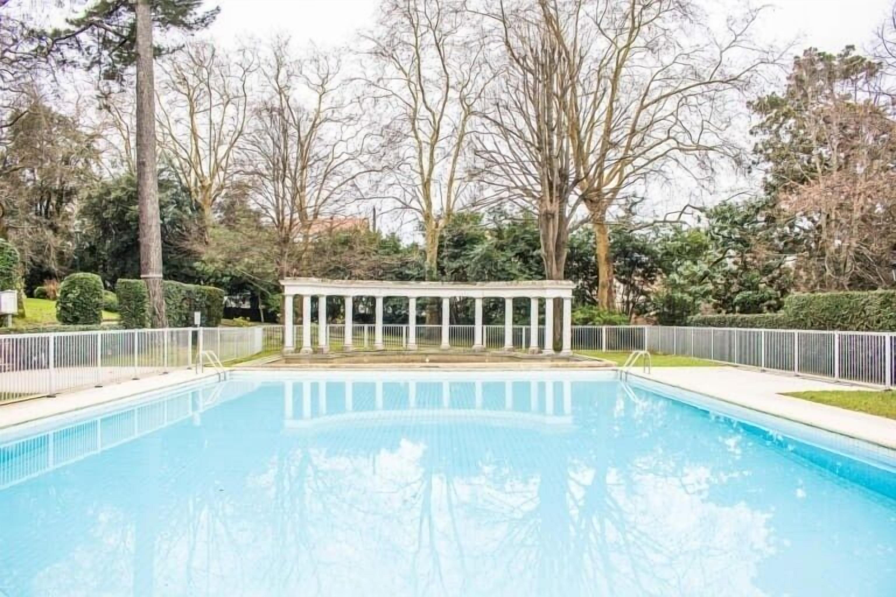 A rectangular swimming pool with a white fence surrounding it.