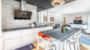 Een moderne keuken met een centraal eiland, witte kasten en een ingebouwde oven.