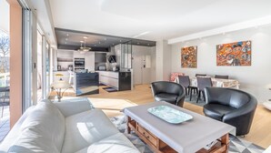 Een moderne woonruimte met een bank, eettafel, stoelen en een keukenhoek.