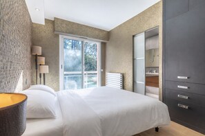 Una camera da letto moderna con un letto grande, un armadio e una finestra vista alberi.