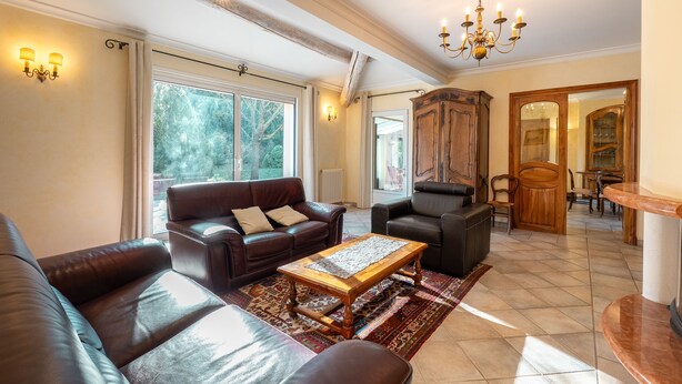 A spacious living room with a leather sofa, a wooden coffee table, and a chandelier. - Maison provençale de Cabriès - 20min de Marseille (Cabriès)