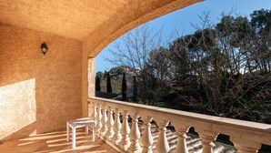 A balcony with a white balustrade, a white table, and a view of trees and hills. - Maison provençale de Cabriès - 20min de Marseille (Cabriès)