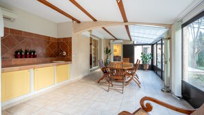 A spacious kitchen with yellow cabinets, a dining area with wooden chairs, and a large window providing a view of the outdoors. - Maison provençale de Cabriès - 20min de Marseille (Cabriès)