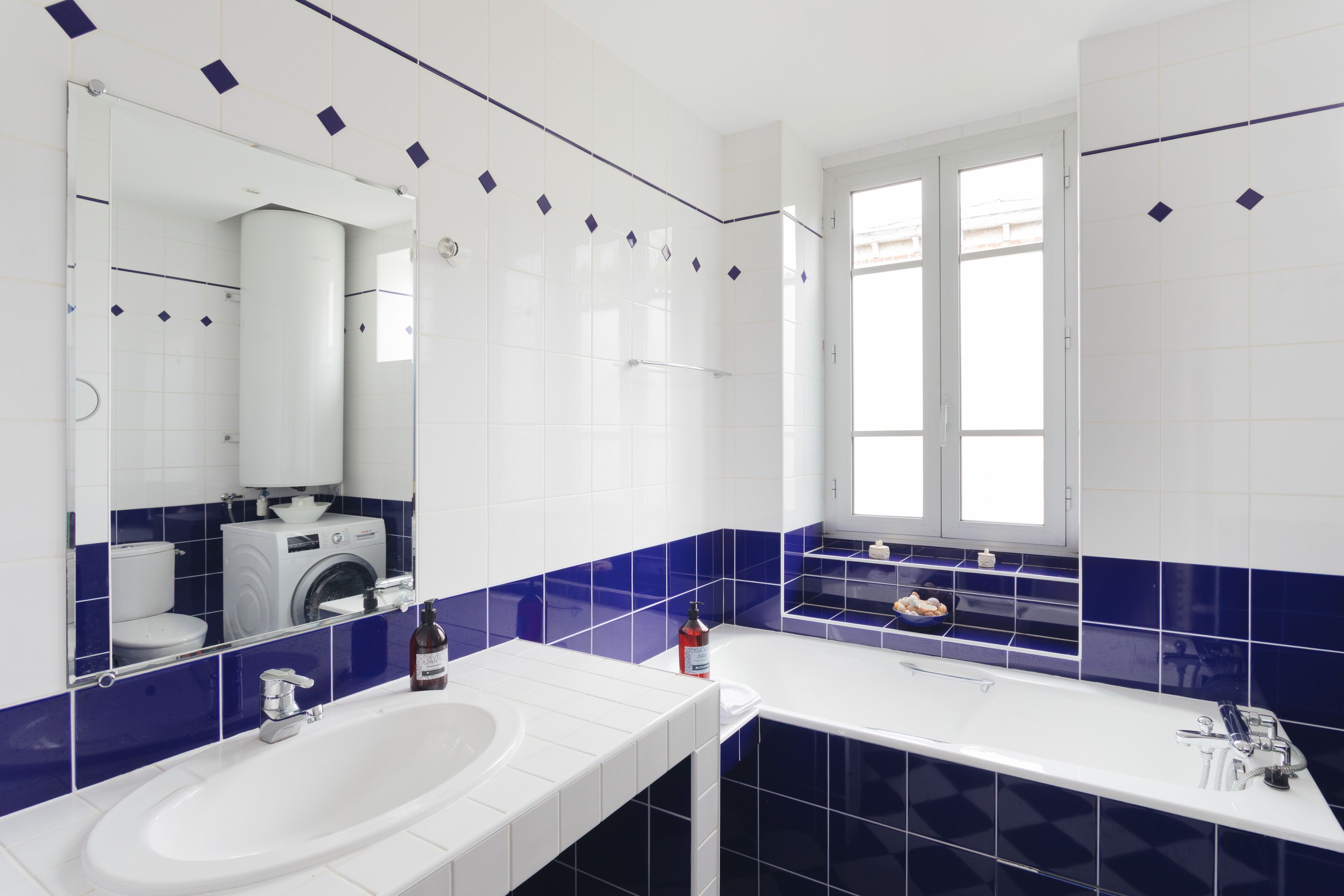 Un baño moderno con lavamanos blanco, bañera y ventana.