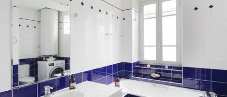 Un baño moderno con lavamanos blanco, bañera y ventana.