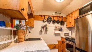 Une cuisine avec des meubles de rangement en bois, un réfrigérateur en acier inoxydable, une cuisinière et un porte-casseroles suspendu.
