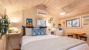 Une chambre confortable avec un lit, une table de chevet, une lampe et une fenêtre.