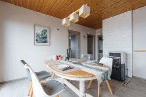 Ein Essbereich mit einem Holztisch, Stühlen und einer weißen Backsteinwand.