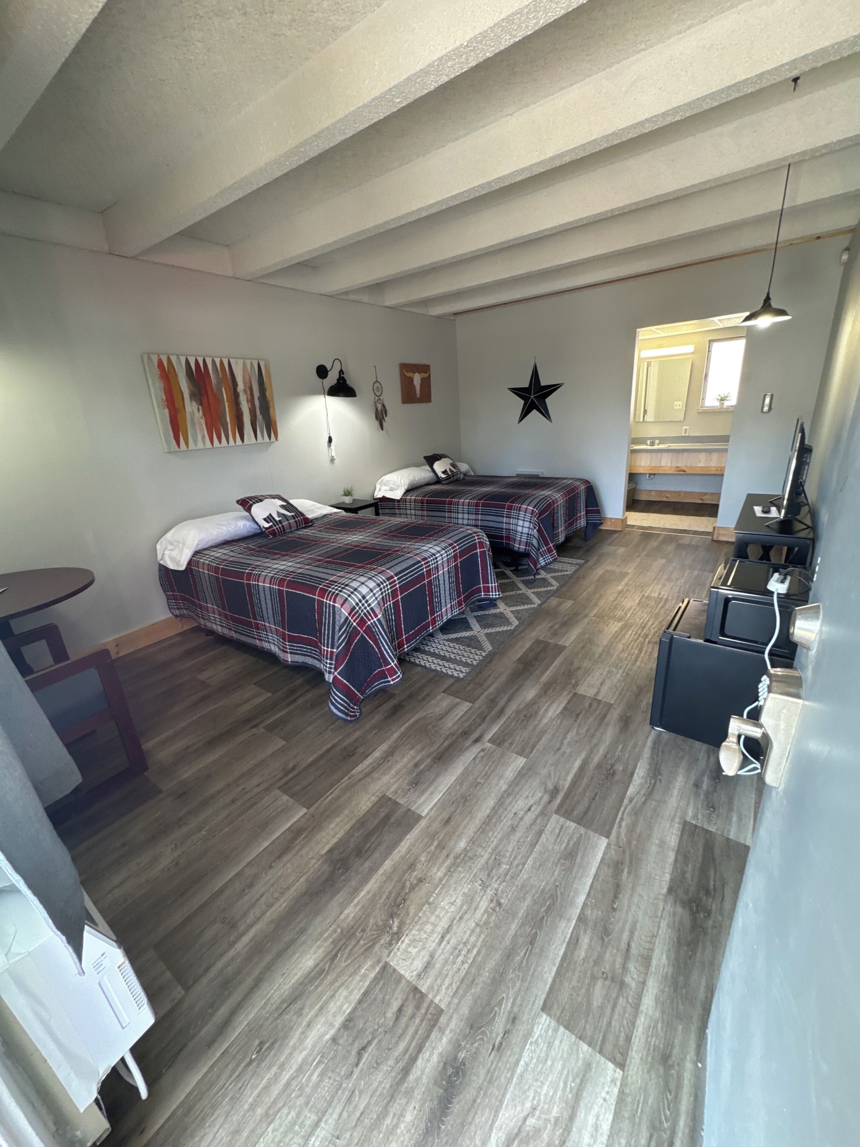 Una habitación con dos camas, un escritorio y un kitchenette.