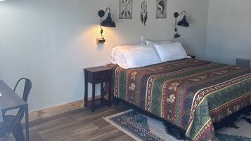 A bedroom with a bed, bedside lamps, a small table, and a chair.