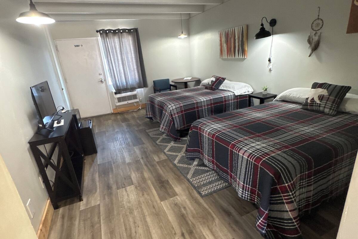 Una habitación con dos camas, un escritorio, una silla y una mesita.