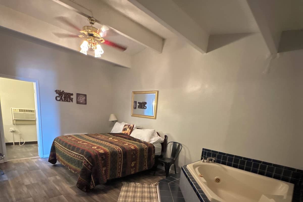Un dormitorio con cama, una silla, un baño con bañera y un pasillo.