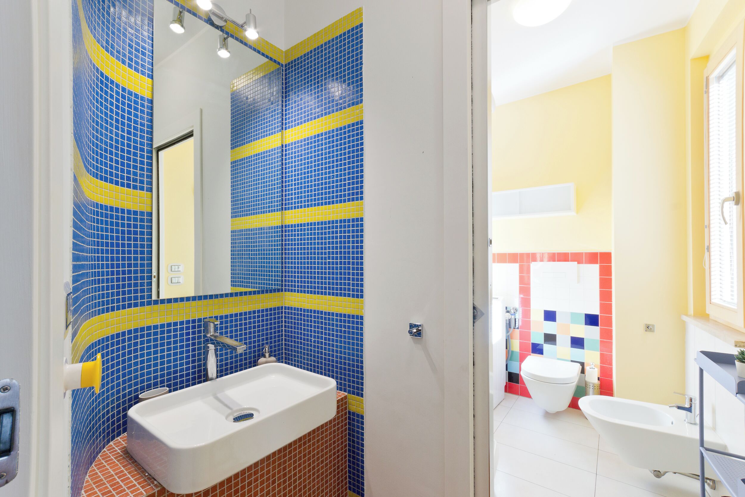 Un baño con lavamanos, espejo y inodoro.