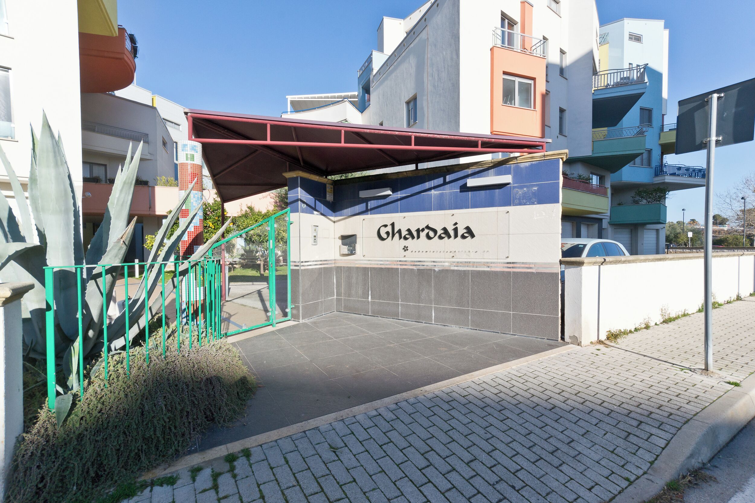 Ein begrenzter Zugang zu einem Gebäude namens 'Ghardiaia' mit einer überdachten Treppe und einem gepflasterten Weg, der zum Eingang führt.