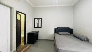 Una habitación pequeña y limpia con cama, mesita de noche y un espejo en la pared.