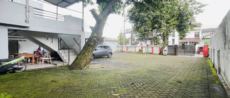 Un patio empedrado con un árbol, una escalera y un coche aparcado.