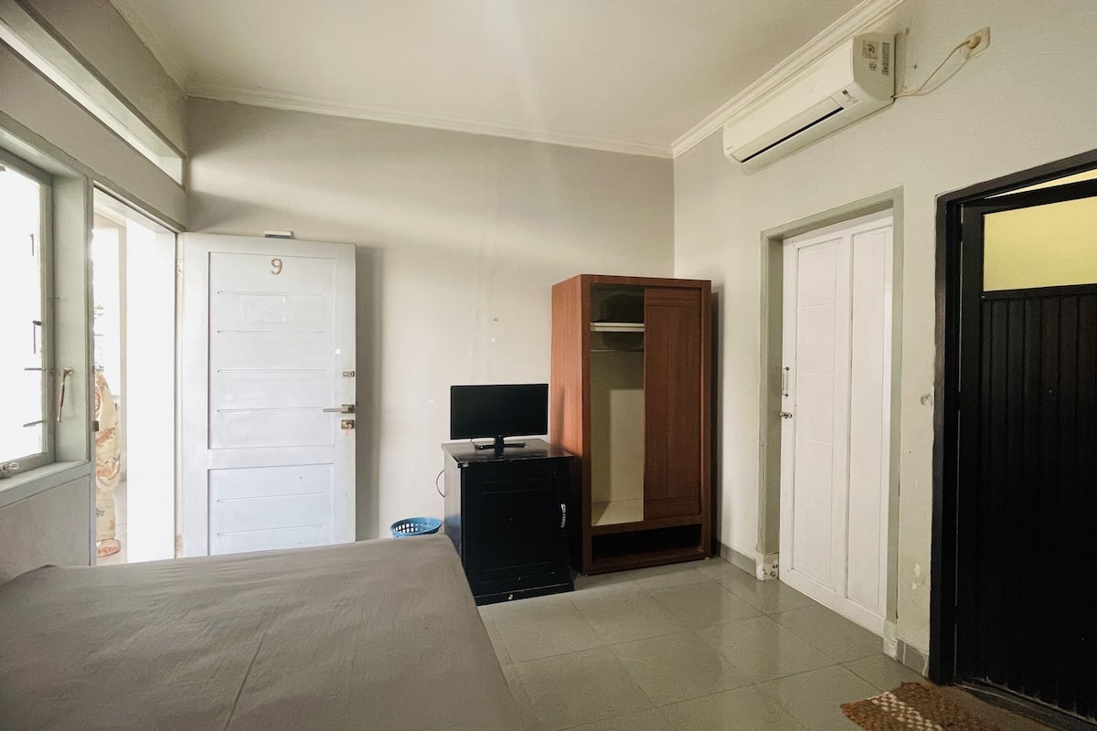 A room with a bed, a wardrobe, a television, and a door marked with the number 9.