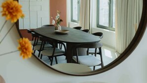 A round mirror reflecting a dining area with a table, chairs, and a vase with flowers. - Large apartment with balcony, 3 BR and 2 Bathrooms (Antwerpen)